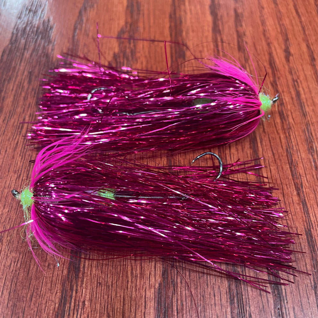 Two purple fishing flies on a wooden surface