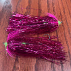 Two purple fishing flies on a wooden surface