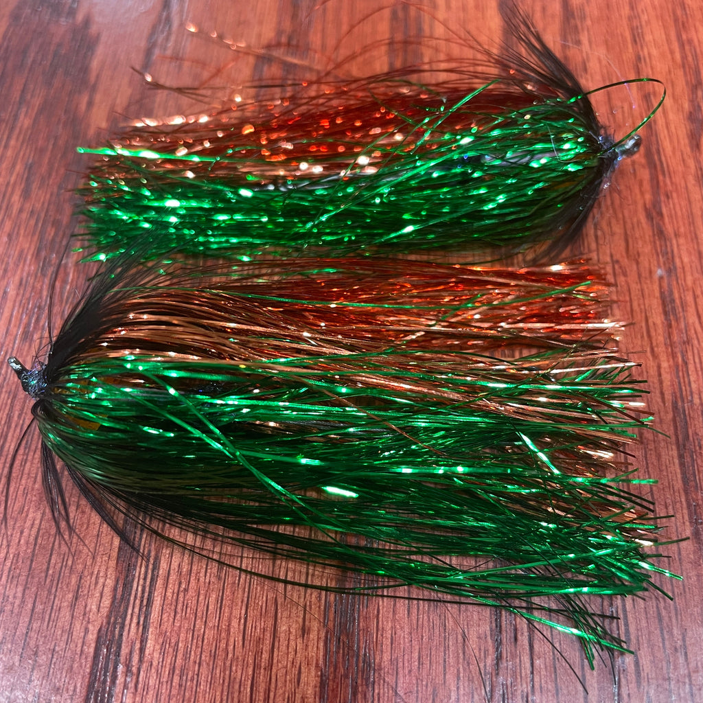 Two artificial Streamer patterns designed for steelhead fishing, laid out on a wooden surface.