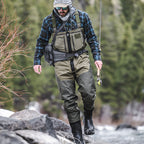 Man in outdoor gear walking along a rocky stream with trees in the background with Simms M's Freestone Z Bootfoot Waders - Rubber Sole
