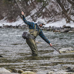 Person fly fishing in a snowy river landscape wearing Simms M's Freestone Z Bootfoot Waders - Rubber Sole