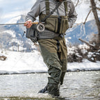 Person fly fishing in a snowy landscape wearing a Simms M's Freestone Z Bootfoot Waders - Rubber Sole and holding a rod.