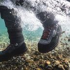 Person wearing black Simms MEN's G3 Guide Wading Boot - Vibram Soles with red laces standing on a rocky underwater floor.