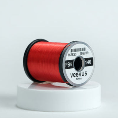 Red spool of fly-tying thread with 'veevus' branding on a white background
