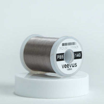 Gray spool of fly-tying thread with 'veevus' branding on a white background