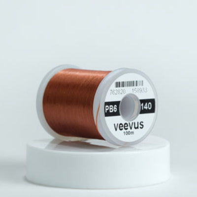 Brown spool of fly-tying thread with 'veevus' branding on a white background