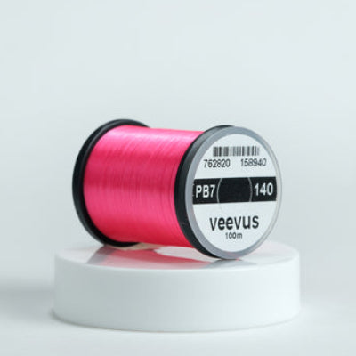 Pink spool of fly-tying thread with 'veevus' branding on a white background