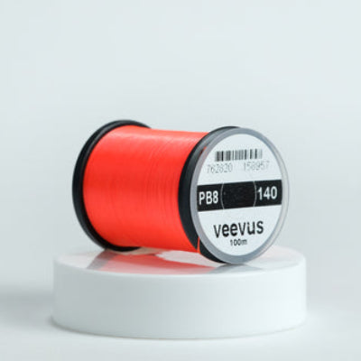 Red spool of fly-tying thread with 'veevus' branding on a white background