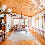 Living room with wooden floors and ceiling, featuring a couch, coffee table, and decorative items.