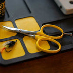 Yellow Loon Ergo Tungsten Carbide Curved Micro Tip Scissors w/ Precision Peg on a fishing fly tray with a fishing lure visible.