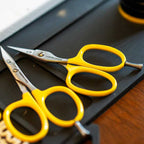 Two pairs of yellow-handled Loon Ergo Tungsten Carbide Universal Scissors w/ Precision Peg on a dark surface.