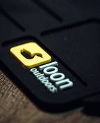 Close-up of a black product with a yellow and white logo on a wooden surface