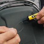 Person applying a UV sensitive adhesive to a clear plastic object with a black and yellow tool.