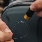 Person holding a fishing line with a hook, with a blurred background