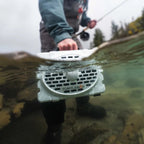 Turtlebox Original Gen 3 speaker submerged in water with a person fishing in the background