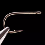 A close-up image of a Daiichi 1650 bronze fishing hook with a round bend and a straight-eye, featuring a short shank and a hook eye visible in the foreground.