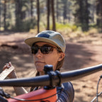 Person wearing sunglasses and a cap in a forest setting