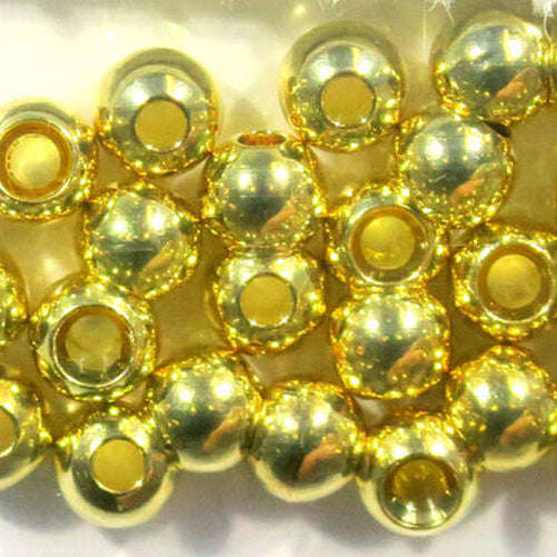Gold metal beads for fly tying on a white background