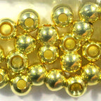 Gold metal beads for fly tying on a white background