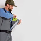 A fisherman with a pair of gray zippered Orvis men's PRO fly-fishing waders with suspenders and boots.
