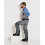 A fisherman with a pair of gray zippered Orvis men's PRO fly-fishing waders with suspenders and boots.