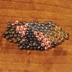 Assorted Hareline Cyclops Bead Eyes for fly tying on a wooden surface