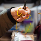 Hand holding yellow scissors cutting a string with a blurred background