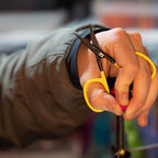 Hand holding yellow-handled scissors with a blurred background