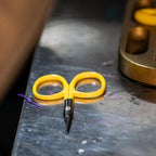 Yellow scissors on a metal surface with a blurred background