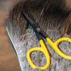 Yellow-handled scissors on a deer hair patch with a blurred background
