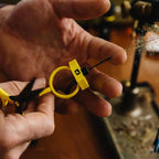 Hand holding a small yellow and black Loon Gator Grip Dubbing Spinner with a blurred background