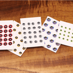 Assorted color eye Hareline 3D Adhesive Holographic Eyes on a wooden surface