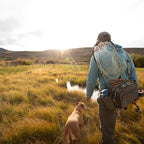 Angler wearing a Fishpond Waterdance Pro Guide Pack outdoors with a dog