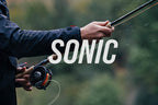 A two-handed Sage Sonic Switch and Spey Fly Rod with a cork handle and a graphite rod body, featuring charcoal and gunmetal trim wraps.