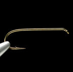 Gold-colored Daiichi 1280 dry fly fishing hook on a black background