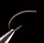 A close-up of a single Daiichi 1160 fly fishing hook with a bronze finish.
