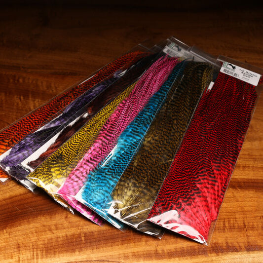 Packaged Hareline Half Grizzly Saddle in various colors on a wooden surface