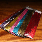 Packaged Hareline Half Grizzly Saddle in various colors on a wooden surface
