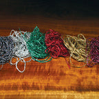 Colorful Hareline Holographic Braid strands on a wooden surface