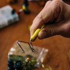 Yellow Loon whip finisher tool with a metal hook on a blurred background