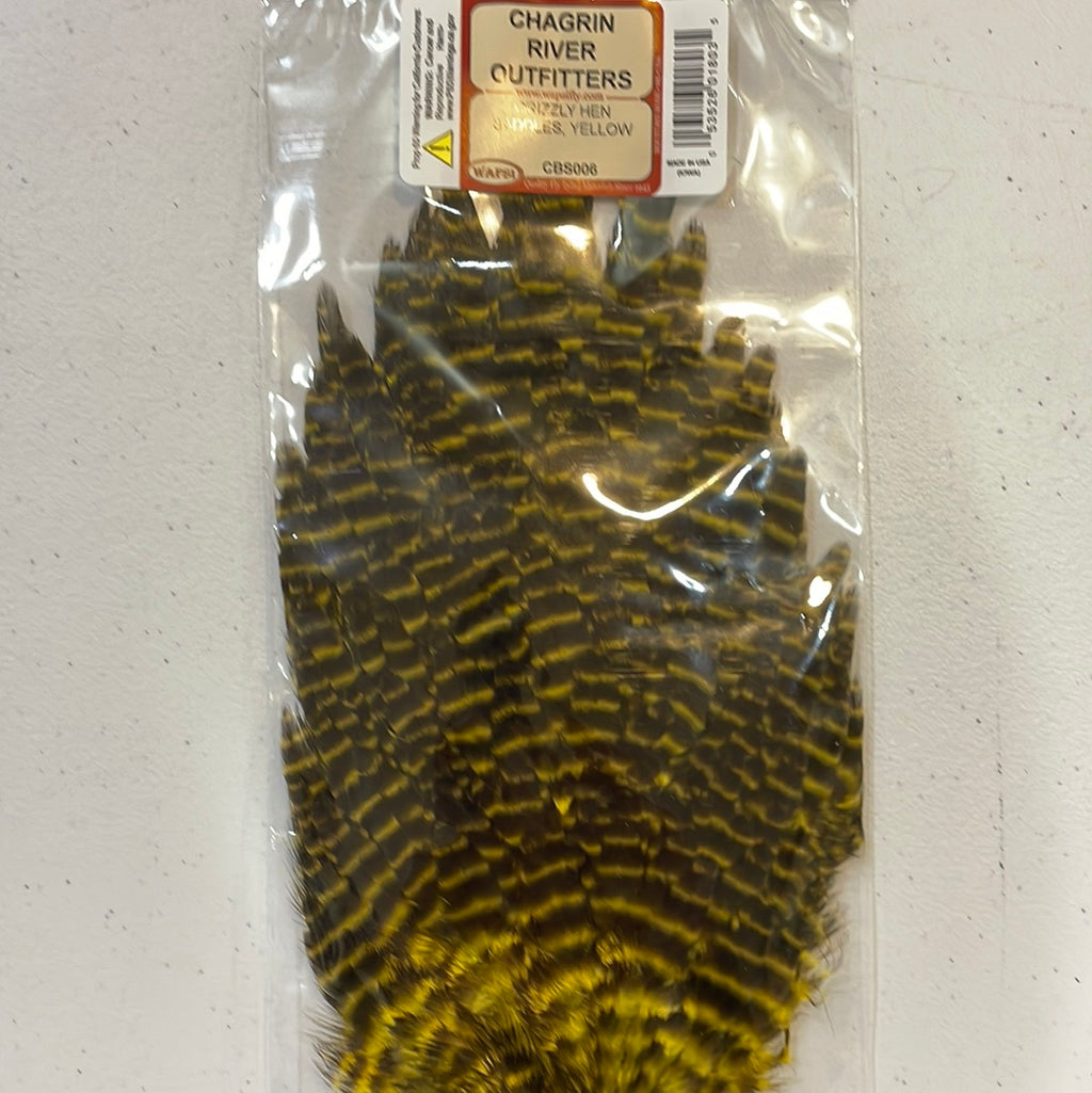 Packaged saddles of Wapsi Grizzly Hen, primarily brown and black in color, intended for use in fly tying.