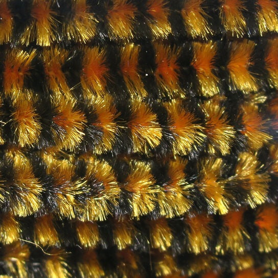 Close-up of a textured Hareline Variegated Medium Chenille with orange, black, and gold colors.