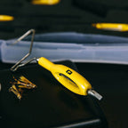 Yellow Loon whip finisher tool with a yellow handle on a dark surface, with a blurred background.