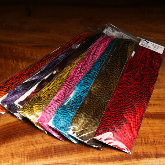 Packaged Hareline Half Grizzly Saddle in various colors on a wooden surface