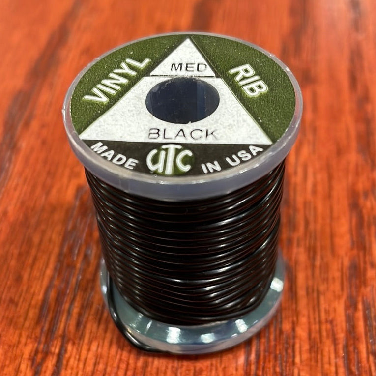 Spool of black Wapsi UTC Vinyl Rib ribbon on a wooden surface