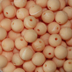 A close-up image of peach round fishing beads with a hole in the center for stringing purposes.