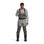 Person wearing Simms Men's Freestone Stockingfoot Waders, featuring gray upper and lower layers with black suspenders and red adjustment straps.