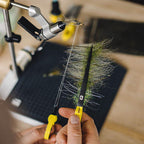 Person crafting a fly fishing lure with Loon Ergo D-Loop Tweezer on a blurred background