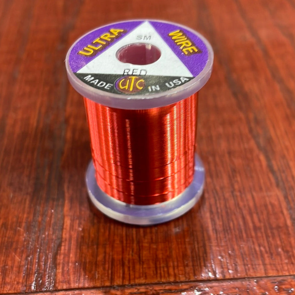 Spool of red Wapsi Ultra Wire UTC with a purple label on a wooden surface