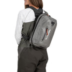 Person wearing a gray backpack with a visible brand logo on a white background
